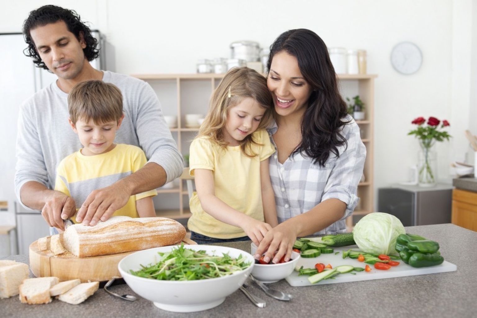 Familj lagar mat ihop: skär bröd och grönsaker vid köksbänk