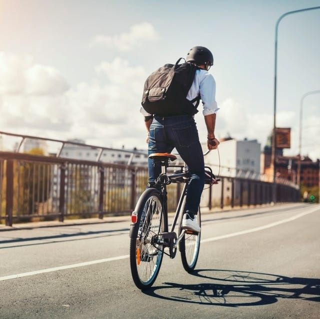 Person cyklar över en stadsgata med ryggsäck och hjälm