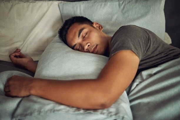 Man sover lugnt på sidan i en säng med kuddar